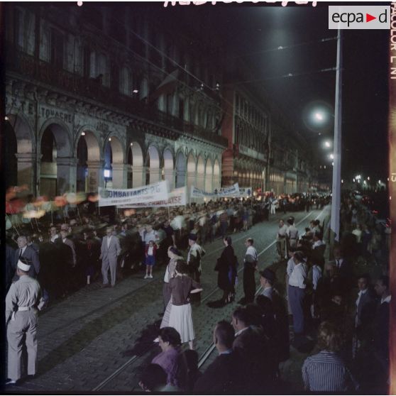 Défilé de nuit de la population d'origine européenne dans une rue d'Alger.