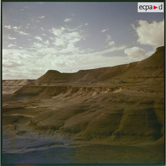 Une colonne de camions et engins blindés à flanc de montagne.