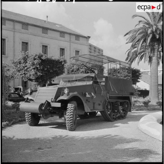 Half-track devant un bâtiment.