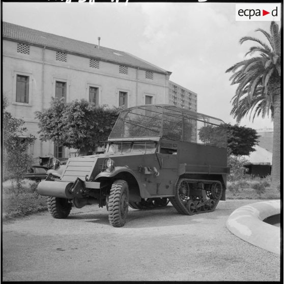 Half-track devant un bâtiment.
