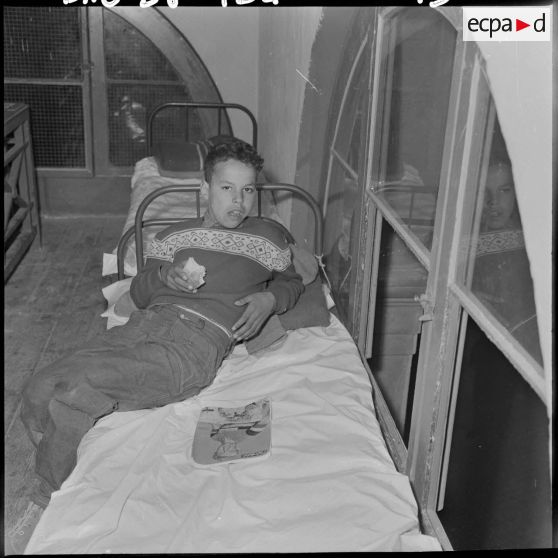 Portrait d'un enfant du foyer de jeunesse de la rue Bab-El-Oued à Alger, en train de manger.