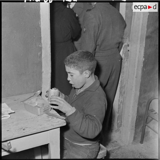 Portrait d'un enfant du foyer de jeunesse de la rue Bab-El-Oued à Alger, en train de manger.
