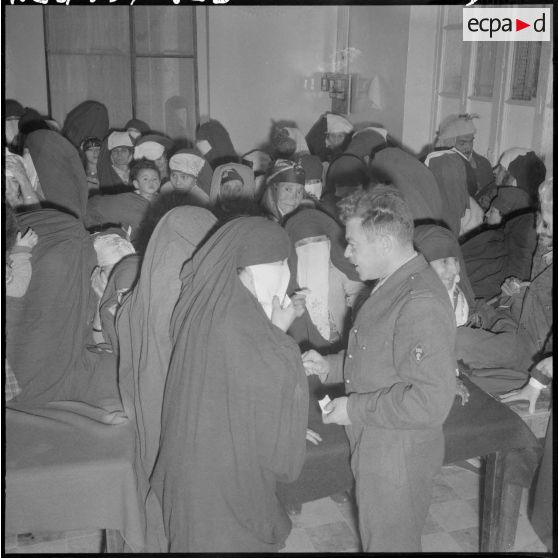 Le docteur du 151ème régiment d'infanterie motorisée (RIM) en conversation avec des malades dans la salle d'attente du centre médico-social.