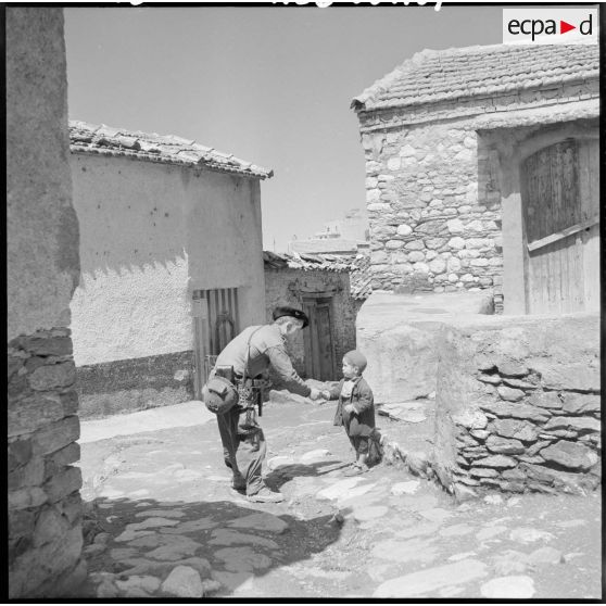 Un chasseur-alpin donne la main à un petit graçon dans la rue du village de Zaknoun.