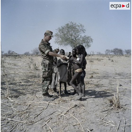 Un soldat français distribue du pain à des enfants tchadiens pendant une halte.