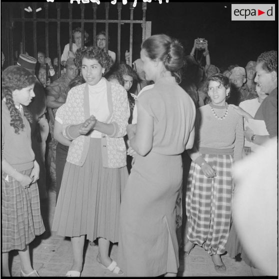 Des femmes regardent leurs voiles brûler, devant le gouvernement général.