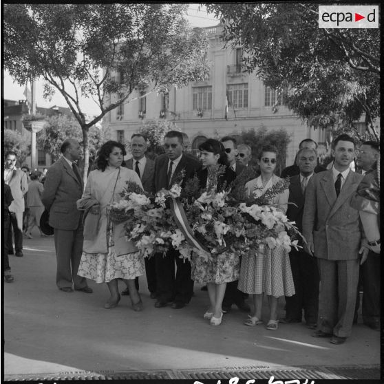 Trois jeunes filles s'apprêtent à déposer une gerbe de fleurs au monument aux morts de Constantine.