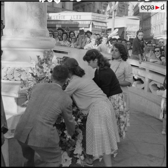 Trois jeunes filles déposent une gerbe de fleurs au monument de la victoire de Constantine.