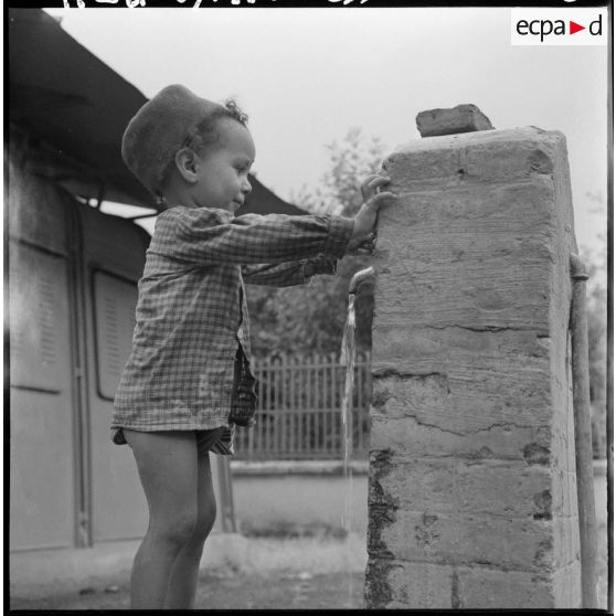 Aumale. Un enfant joue devant une fontaine.
