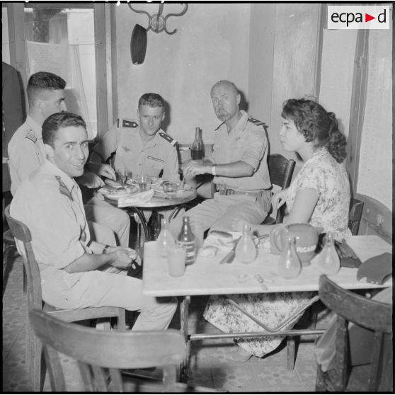 Des officiers déjeunent avec une jeune femme dans un restaurant.