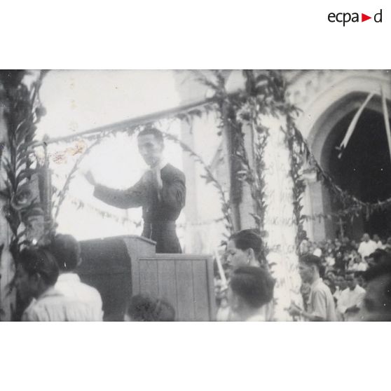 Prêtre dirigeant la chorale durant une cérémonie religieuse à l'église Saint-Philippe à Saigon. [description provisoire]