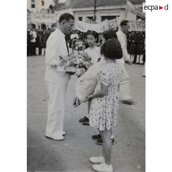 Une gerbe de fleurs en mains, le président du gouvernement de la République de Cochinchine, Le Van Hoach, s'adresse à de jeunes enfants.