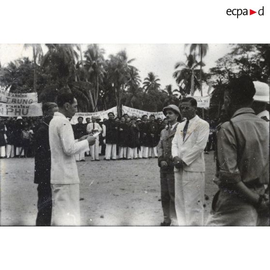 Un homme lit un texte devant le président du gouvernement de la République de Cochinchine, Le Van Hoach, à l'occasion de la tournée de ce dernier à Gia Dinh et à Thu Duc.