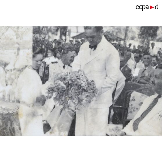 Une jeune fille offre une gerbe de fleurs au président Hoach. [description provisoire]