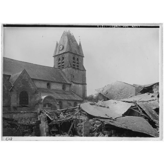 [Ruines devant une église aux murs et clocher encore intacts.]