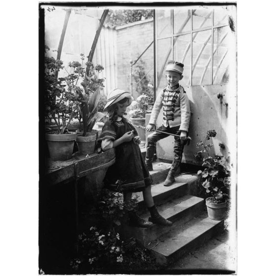 [Deux enfants jouent dans une serre.]