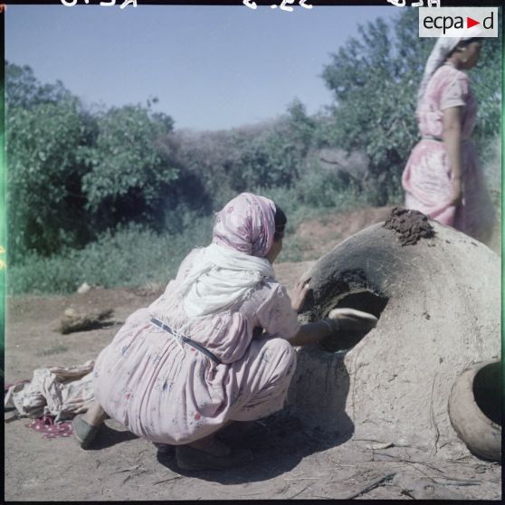 Une femme utilise un four à pain.