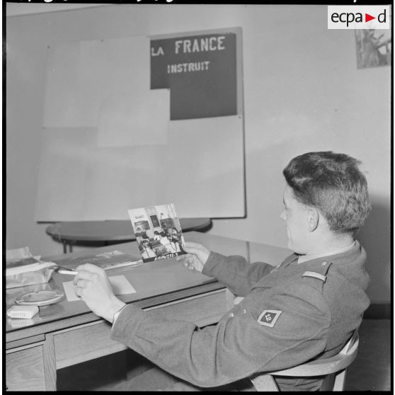 Algérie. 5e bureau. Un stagiaire officier regarde une photo pour la création d'une affiche de propagande.