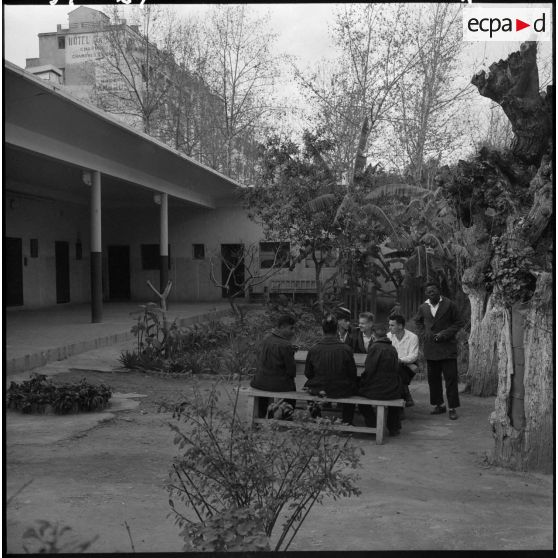 Alger. Hôpital Maillot. Des malades fument dans la cour arborée.