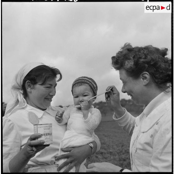 Miliana. Des assistantes donnent du lait concentré sucré à un bébé.