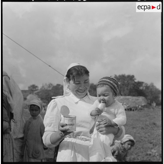 Miliana. Une assistante donne du lait concentré sucré à un bébé.
