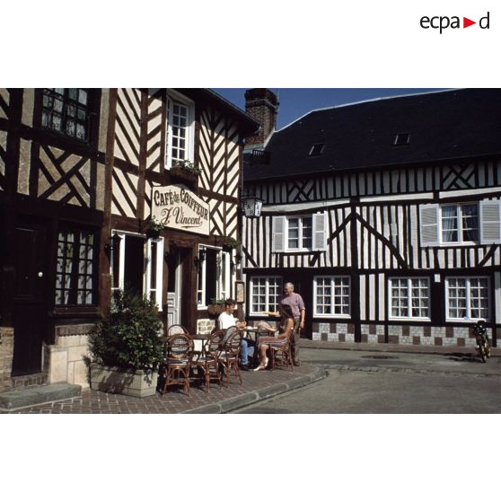 Beuvron-en-Auge (14). Terrasse de café et maisons traditionnelles.