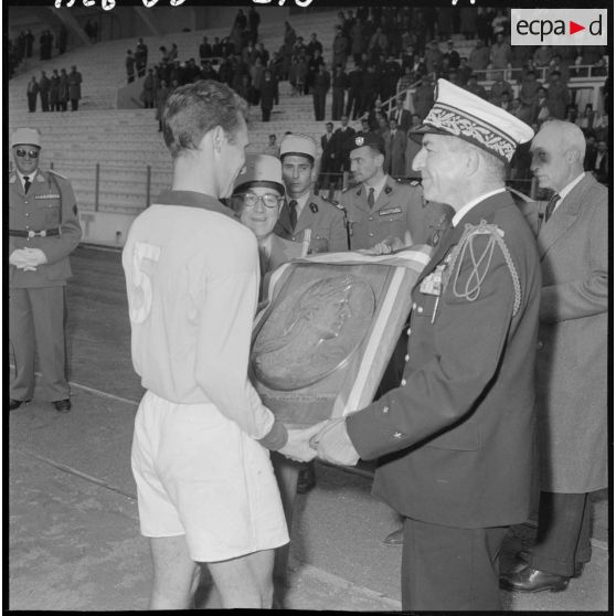 Oran. Stade municipal. Finale du championnat de France militaire. Le général Gambiez et le général Ezano remettent le trophée au capitaine du crops d'armée de Dijon.