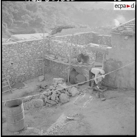 Centre de regroupement de Boudjebâa. Un habitant travaillant dans sa cour.