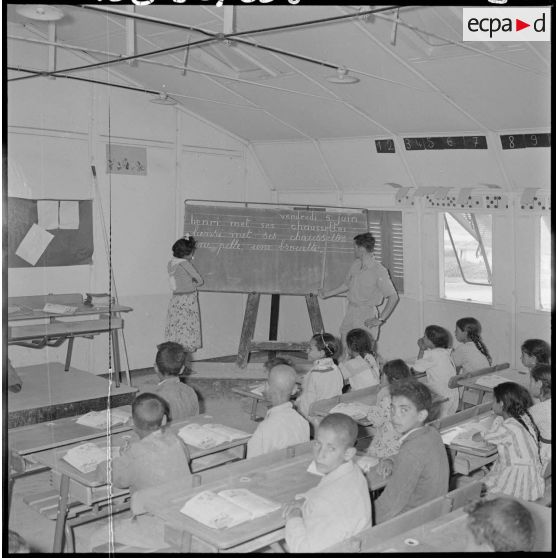 Centre de regroupement d'Ouled Ali. A l'école le sergent du 129e régiment d'infanterie (RI) faisant fonction d'instituteur et une fillette.