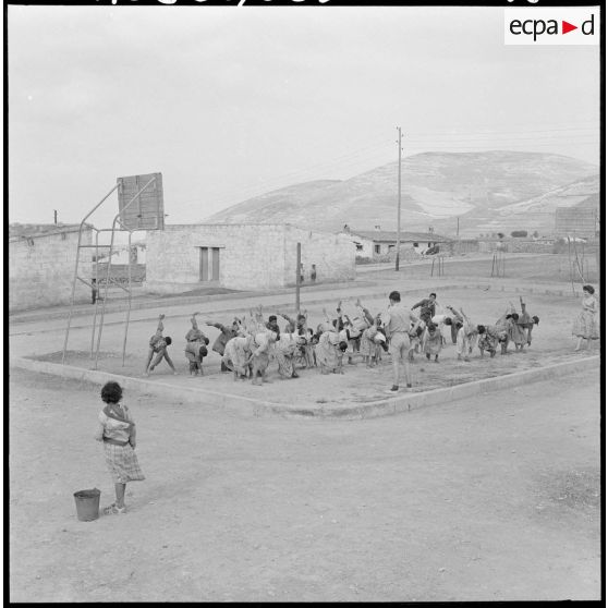 Centre de regroupement d'Ouled Ali. Les enfants sur le terrain de sport faisant des mouvements.
