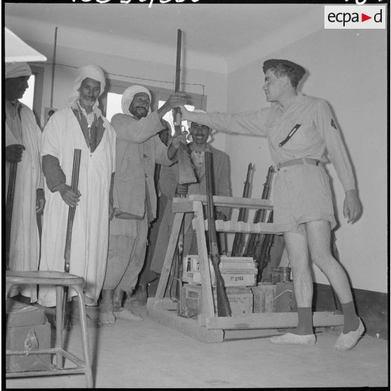 Centre de regroupement d'Ouled Ali. Le sous-lieutenant Payen distribuant des armes aux hommes qui assurent la garde du village.