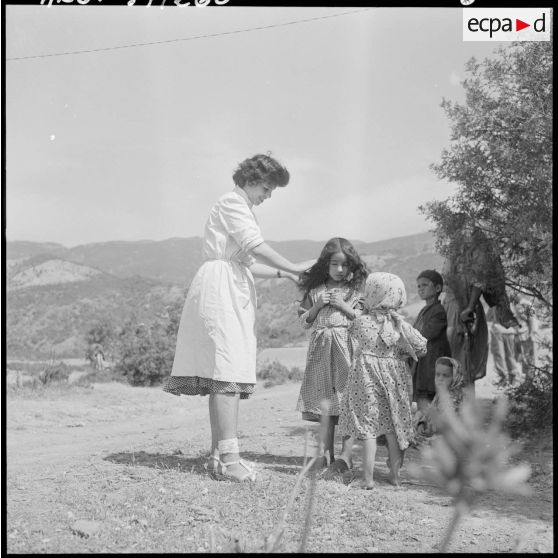 Une adjointe sanitaire et sociale rurale auxiliaire (ASSRA) du groupe de Miliana, peigne une jeune fille.