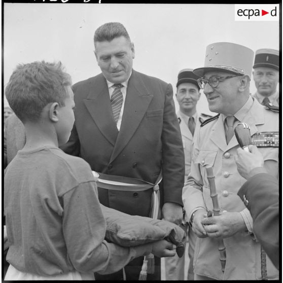Centre de regroupement de Zelemta. Un enfant offre un cadeau au général Gambiez.