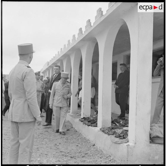 Centre de regroupement de Zelemta. Le général Gambiez regarde des chaussures (devant une mosquée ?).