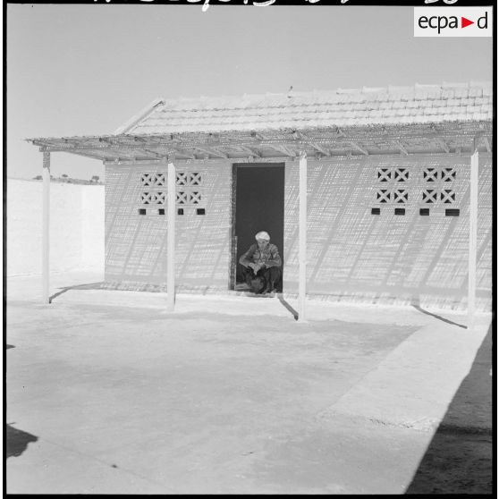 Centre de regroupement de Zelemta. Un homme assis devant une maison.