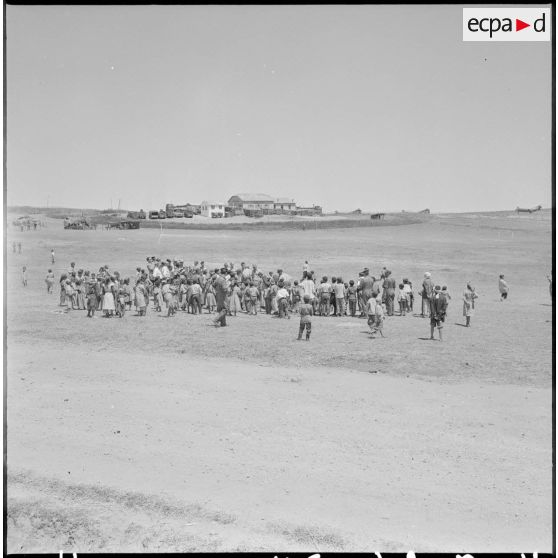 Plan large sur les jeux pratiqués par les enfants, sous les yeux des journalistes en visite au poste d'Aïn-Zana