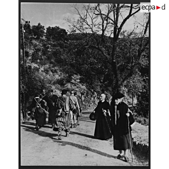 Des goumiers croisent la route d'une vieille femme et d'un prêtre corses lors de leur progression vers Bastia.
