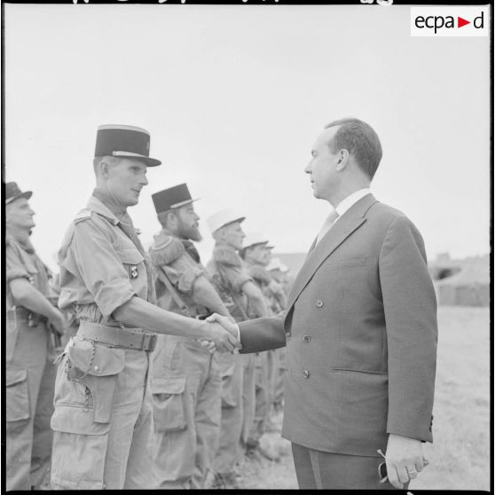 Au poste de commandement (PC) Lama, le Premier ministre Michel Debré serre la main du lieutenant commandant le détachement de la compagnie d'appui du 5e régiment étranger d'infanterie (5e REI), qui rend les honneurs.