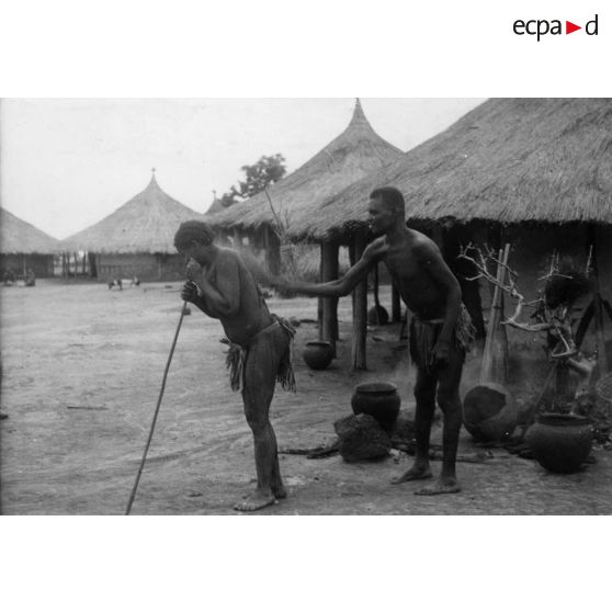 République centrafricaine, Domété à 60 km de Bangui, 1942. Féticheur aspergeant une malade avec une macération de plantes dans de l'eau chaude.