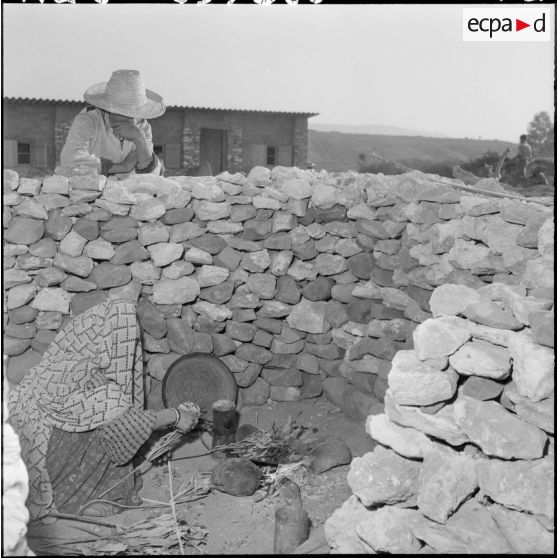 Scène de la vie quotidienne au centre de regroupement de Sidi Naâmane : des femmes préparent le repas.