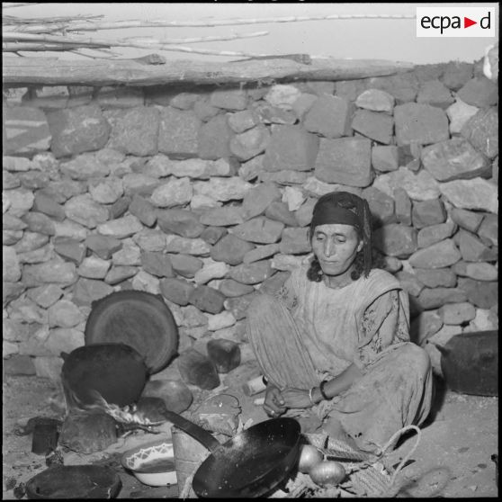 Scène de la vie quotidienne au centre de regroupement de Sidi Naâmane : une femme prépare le repas.