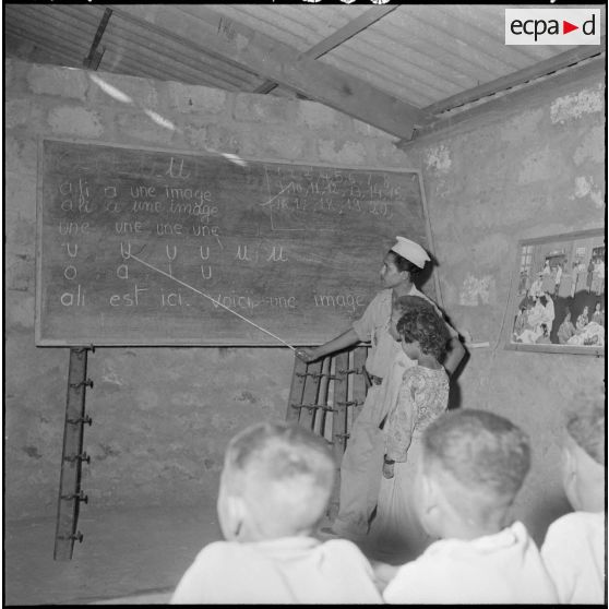 Un jeune moniteur enseigne la lecture aux enfants du centre de regroupement de Sidi Naâmane.