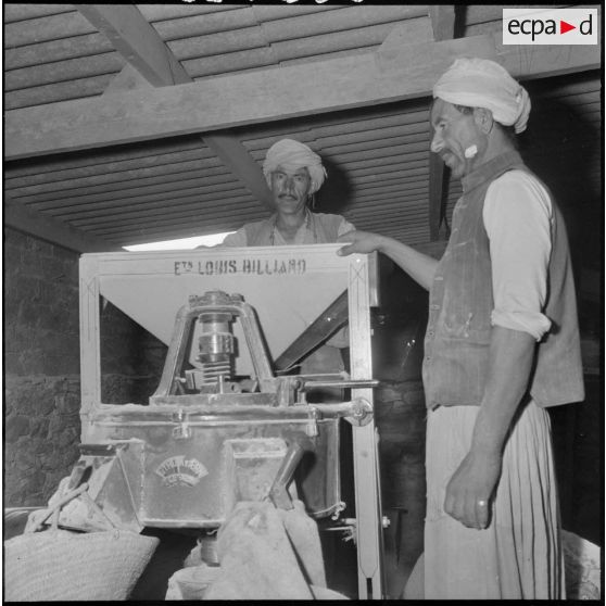 Deux hommes du centre de regroupement de Sidi Naâmane posent à côté d'un moulin à farine.