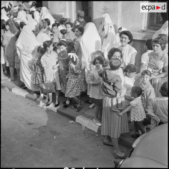 Rassemblement des élèves accompagnés par leurs parents devant l'entrée de l'école primaire.