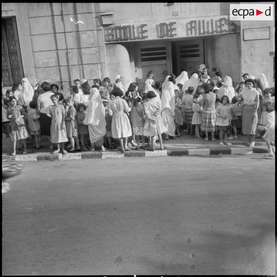Rassemblement des élèves accompagnés par leurs parents devant l'entrée de l'école de filles.