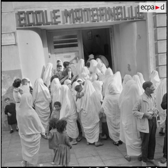 Rassemblement des élèves accompagnés par leurs parents devant l'entrée de l'école maternelle.