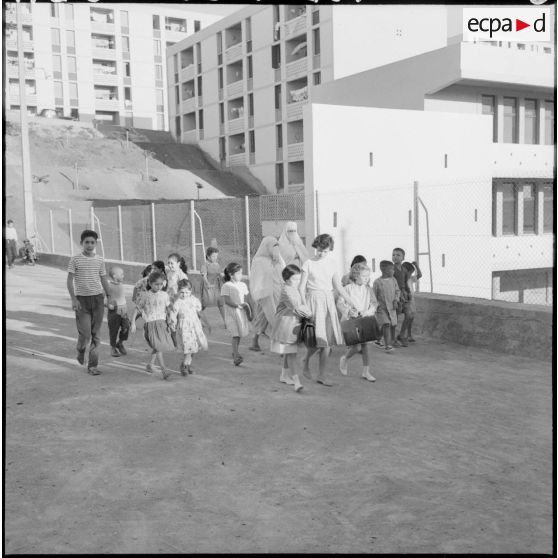 Des écoliers sont suivis et accompagnés par leurs mamans en direction de l'école primaire.