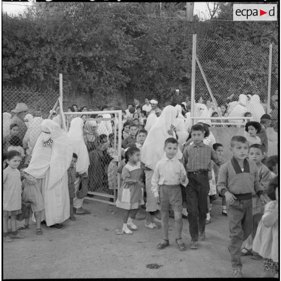 Rassemblement des élèves accompagnés par leurs parents devant l'entrée de l'école.