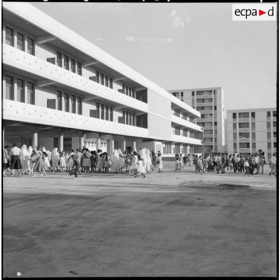 Rassemblement des élèves accompagnés par leurs parents devant l'entrée de l'école.