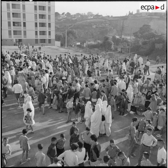 Rassemblement des élèves accompagnés par leurs parents devant l'entrée de l'école.
